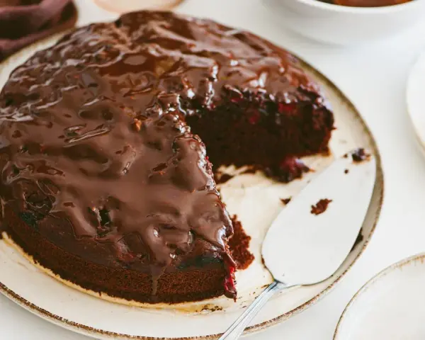 Pyszny brownie z malinami, polane błyszczącą czekoladą. Idealny deser na każdą okazję.