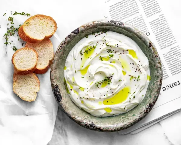 Labneh co to? Kremowy serek jogurtowy, polany oliwą, z ziołami i pieprzem, podany z kromkami bagietki.