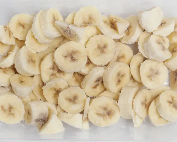 Pokrojone w plasterki banany w pojemniku, pokryte szronem. Tak, banany można mrozić, idealne do smoothie!