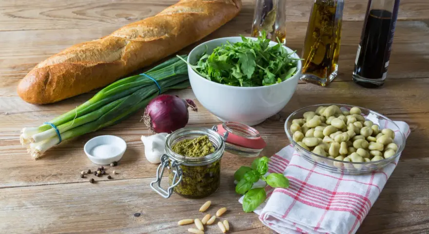 Składniki na pyszne pesto z bobu: świeży bób, bazylia, orzeszki piniowe, czosnek, oliwa, bagietka i rukola.
