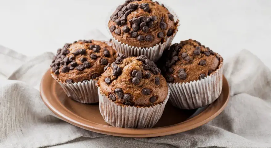 Cztery czekoladowe muffinki w papierowych foremkach, idealne do pieczenia.
