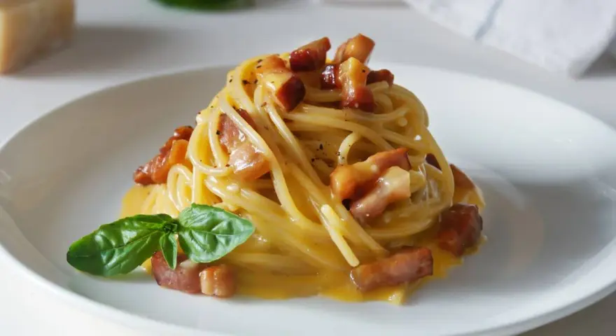 Pyszna carbonara z chrupiącym boczkiem i bazylią. Jaki ser do carbonary? Najlepszy jest parmezan lub pecorino romano.