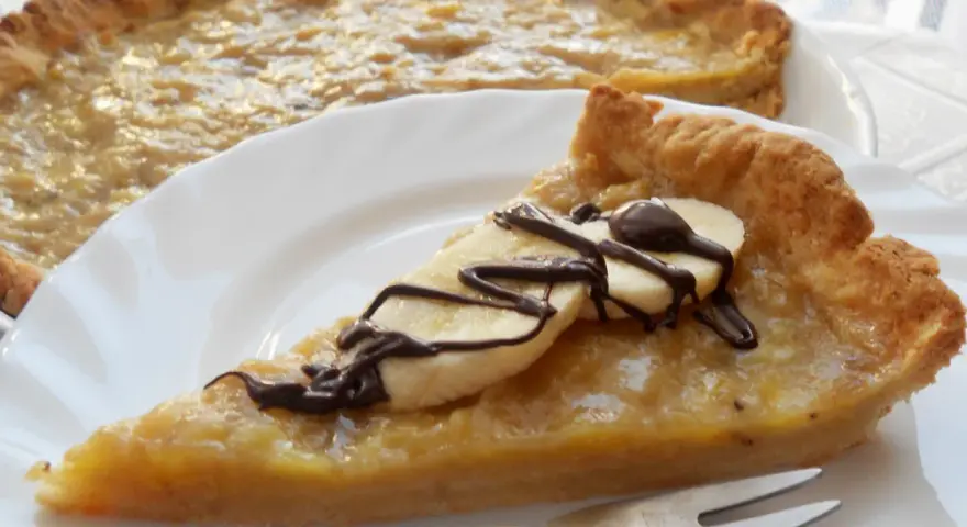 Pyszna tarta z bananami, udekorowana czekoladą i plasterkami banana, czeka na talerzu.