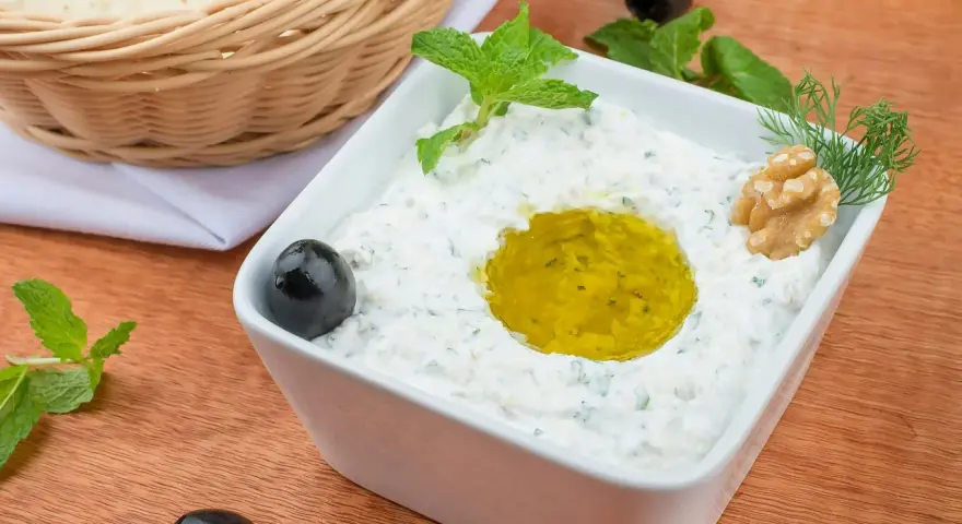 Pyszny sos tzatziki z oliwą, orzechami i miętą, podany z pitą w koszyku.