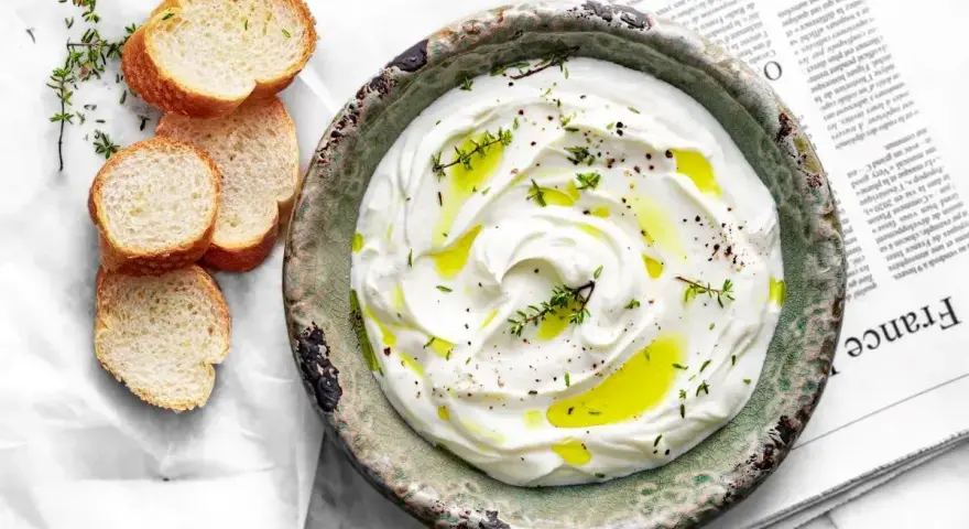 Labneh co to? Kremowy serek jogurtowy, polany oliwą, z ziołami i pieprzem, podany z kromkami bagietki.