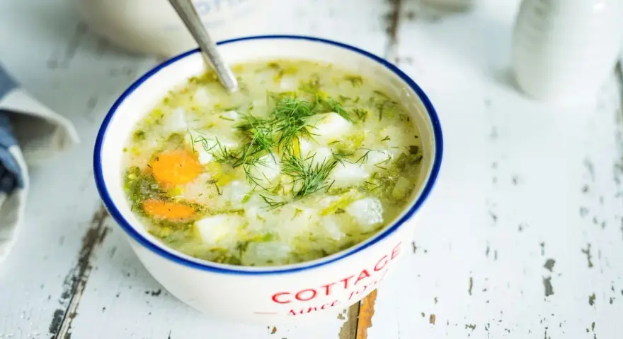 Aromaticzna zupa koperkowa z ziemniakami i marchewką, udekorowana świeżym koperkiem, podana w miseczce z napisem "Cottage".