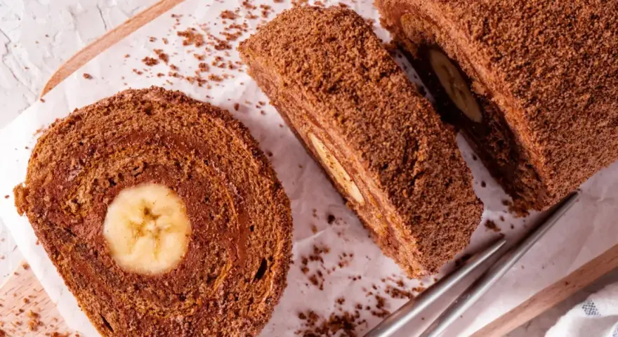 Pyszna rolada biszkoptowa z bananem w środku, posypana kakaową posypką. Idealna na deser.