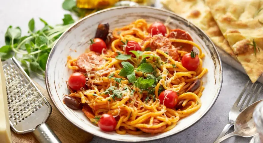 Pyszne spaghetti z chorizo, pomidorkami koktajlowymi i świeżą bazylią, posypane parmezanem. Idealne danie dla miłośników włoskich smaków.