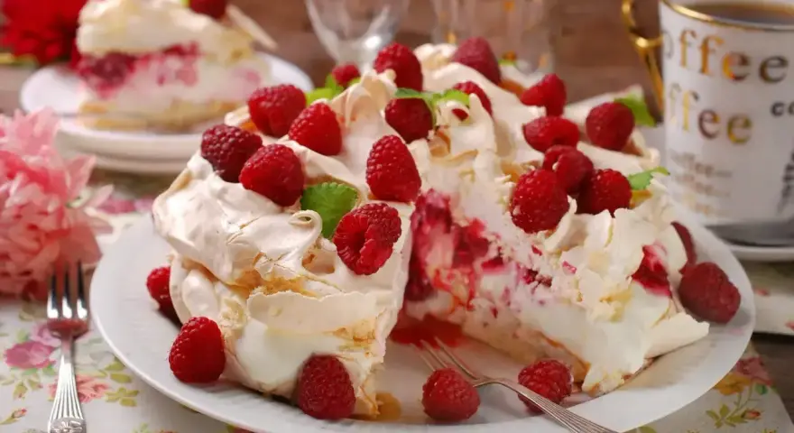 Pyszny tort bezowy z malinami, udekorowany listkami mięty. Idealny deser na letnie popołudnie.