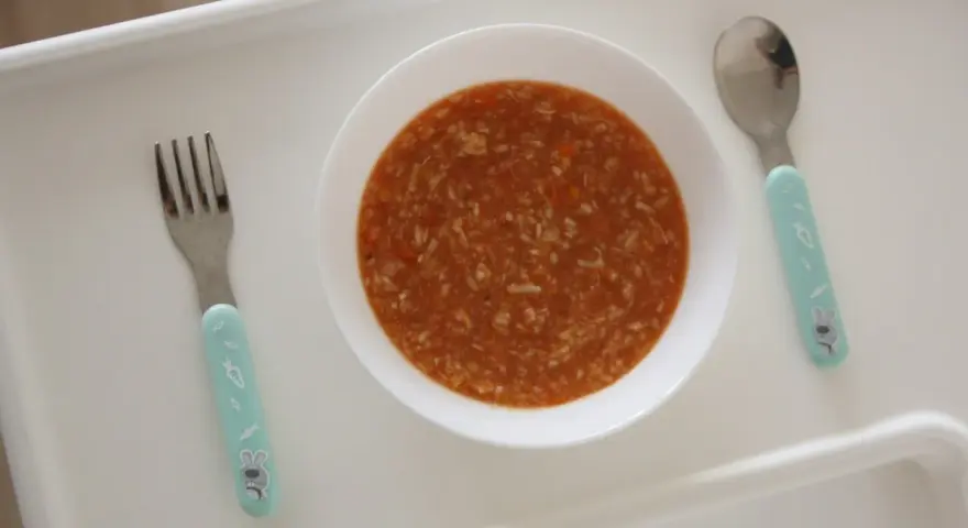 Aksamitna zupa pomidorowa dla dzieci, gotowa do jedzenia. Obok czeka widelec i łyżeczka z uroczymi króliczkami.