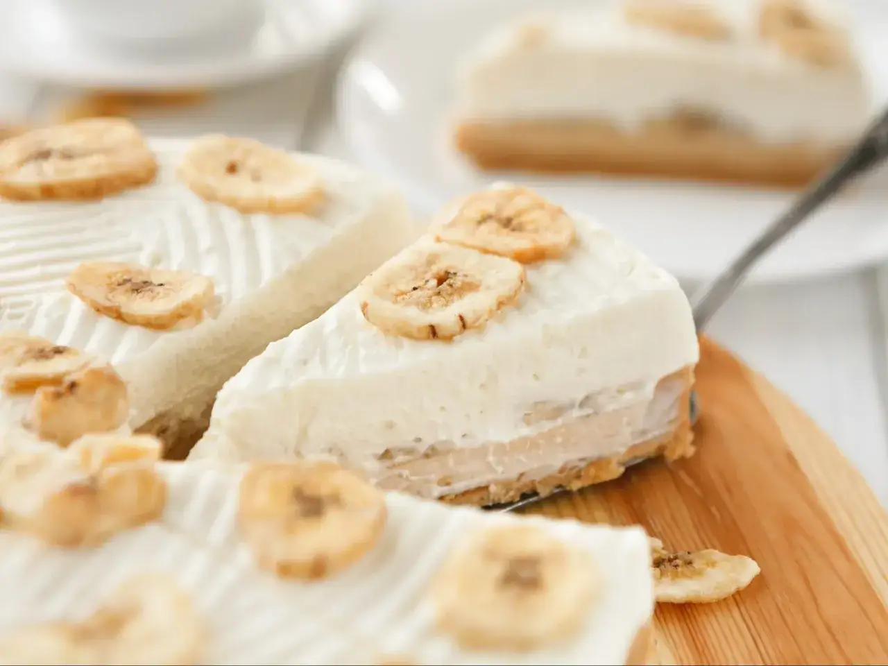 Pyszne ciasto bananowiec z kremem i wiórkami kokosowymi, ozdobione plasterkami suszonego banana.