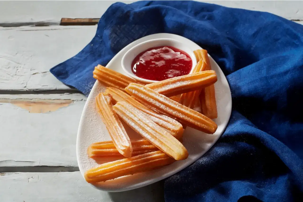 Churros posypane cukrem pudrem, podane z dżemem. Idealny churros przepis na słodką przekąskę.