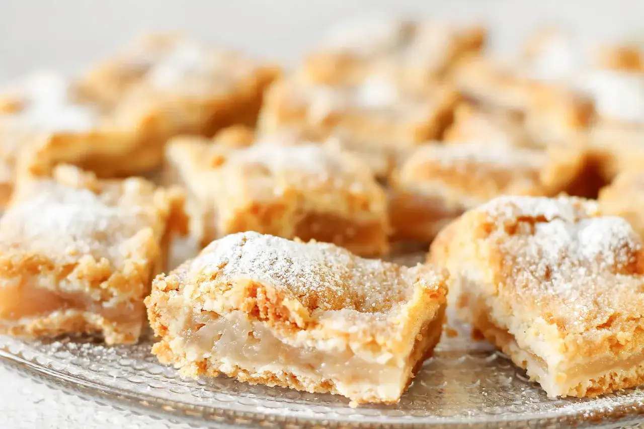 Kawałki pysznej szarlotki na talerzu, posypane cukrem pudrem. Idealne na deser, gdy szukasz sprawdzonego szarlotka przepis.