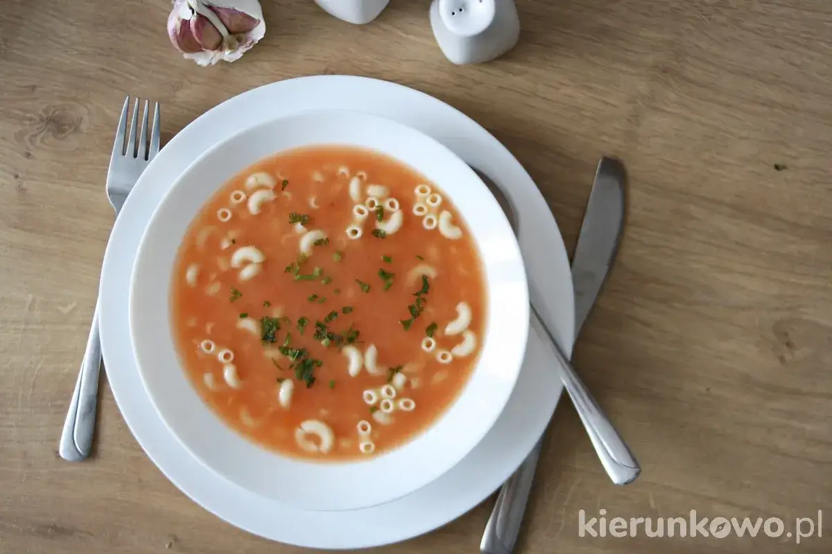 Aksamitna zupa pomidorowa z makaronem w kształcie liter, posypana świeżą natką pietruszki. Idealna na chłodne dni.