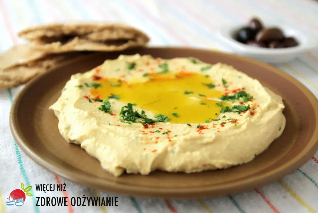Kremowy hummus z oliwą, natką pietruszki i papryką. Idealny hummus przepis na przekąskę z pitą i oliwkami.