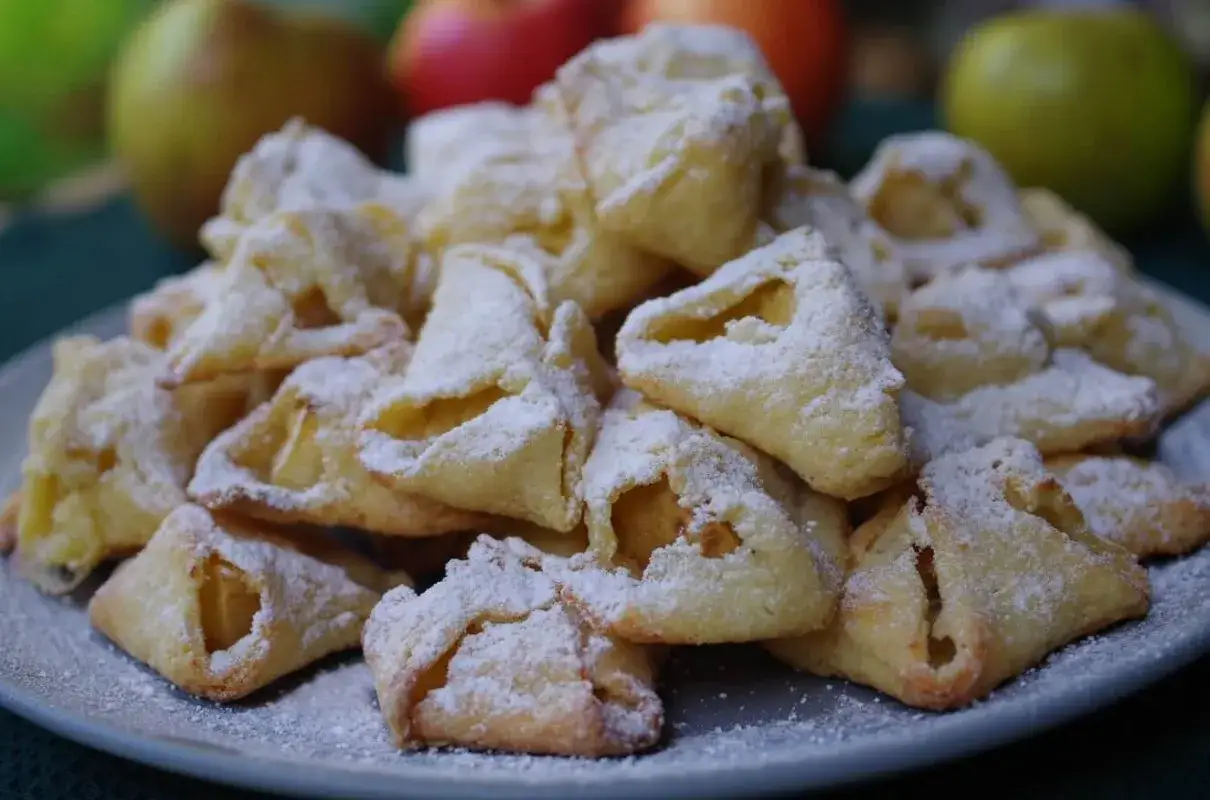 Stos ciasteczek z jabłkami, posypanych cukrem pudrem. Idealne na jesienne popołudnie, jak z przepisu na crumbl cookies.