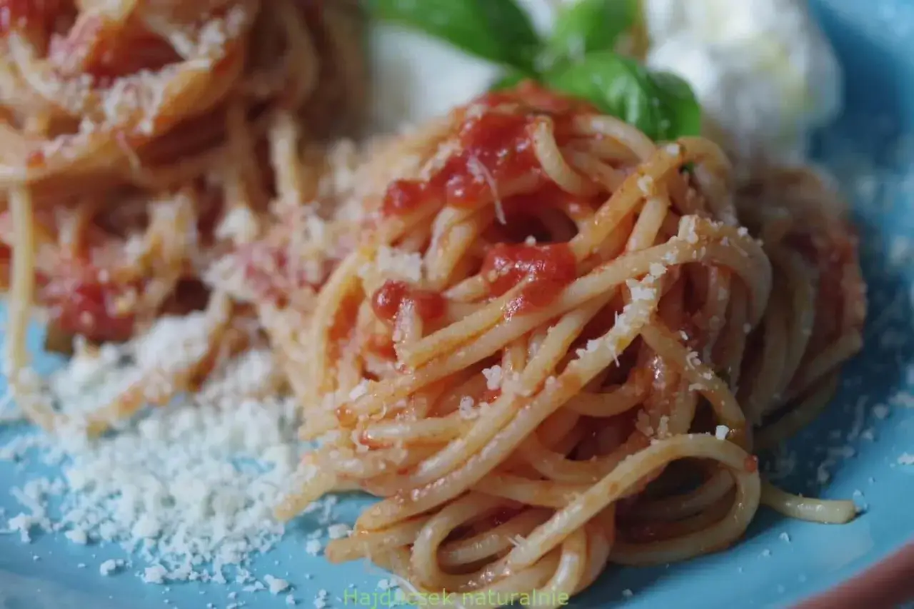 Pyszny makaron spaghetti z pomidorowym sosem, posypany parmezanem i ozdobiony listkami bazylii. Idealny sos do makaronu na szybki obiad.