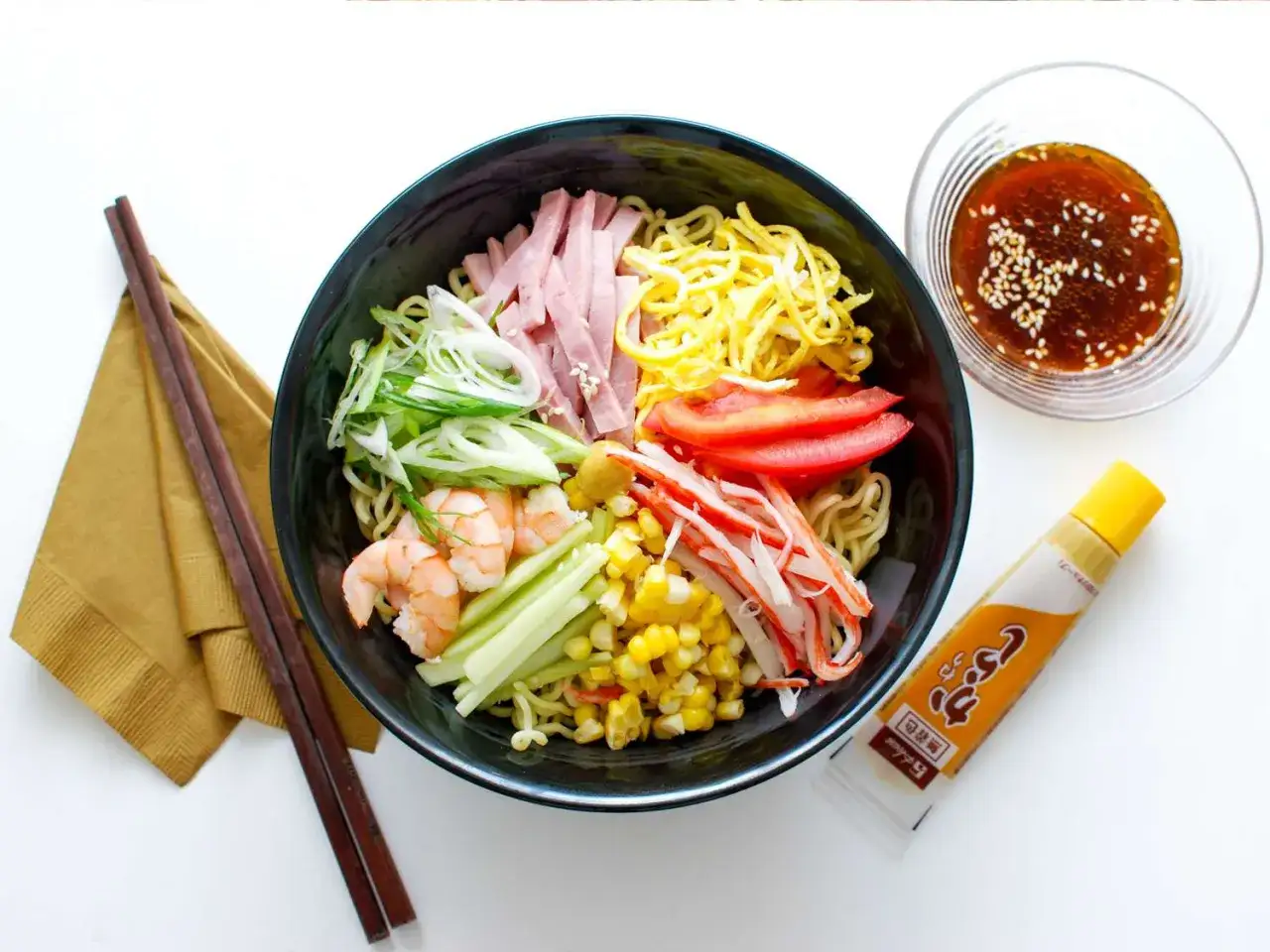 Kolorowa miska z makaronem, krewetkami, szynką, krabem, kukurydzą i warzywami. Idealny letni ramen przepis!