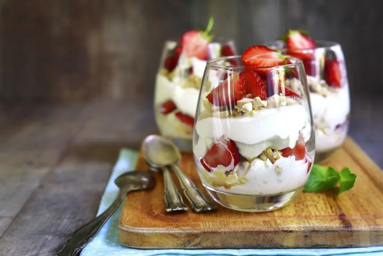 Pyszny deser Eton Mess w szklankach, z bitą śmietaną, truskawkami i kawałkami bezy. Idealny na letnie popołudnie.
