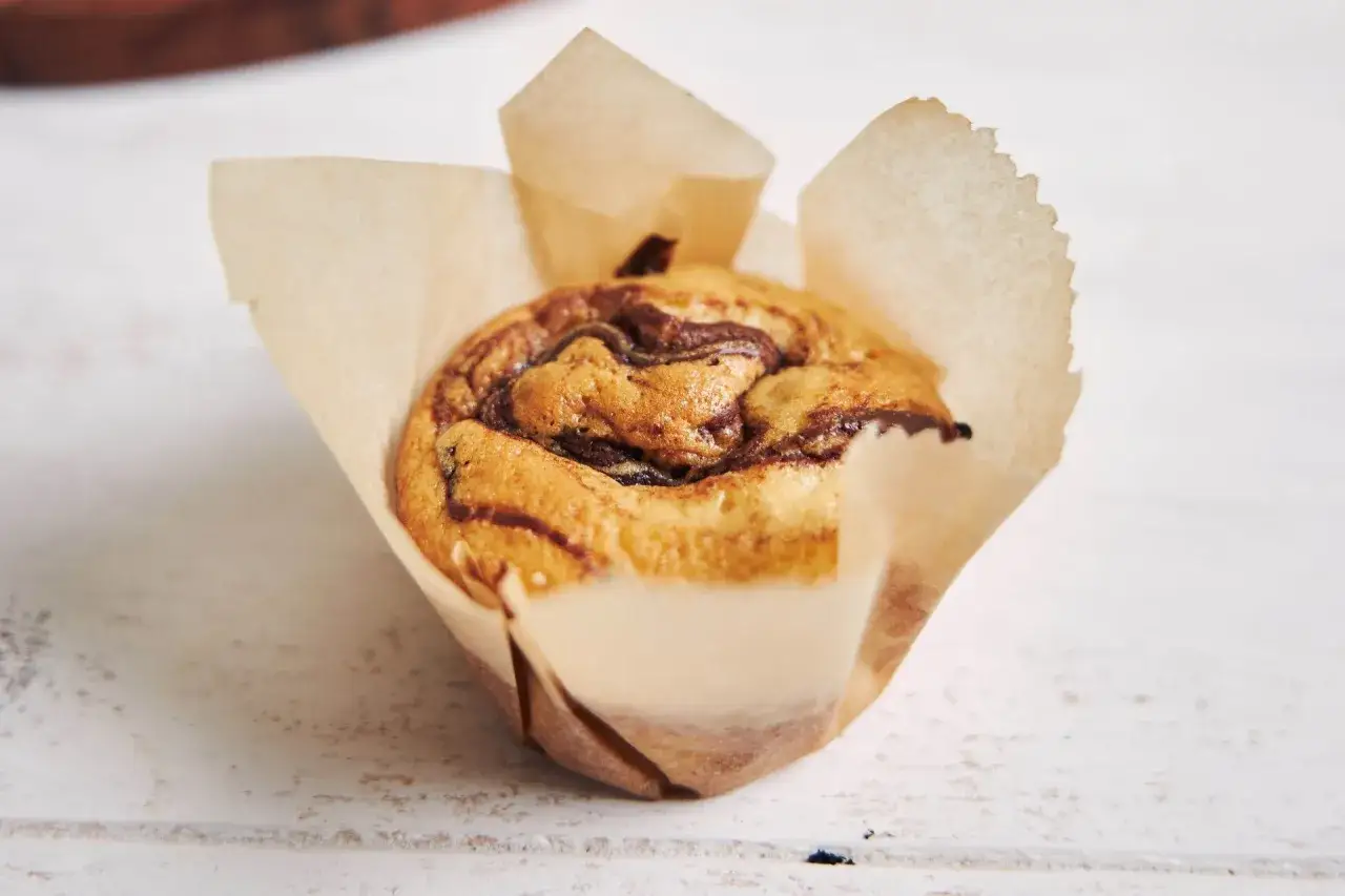 Pyszne muffinki bananowe z czekoladą, pieczone w papierowej formie, kuszą apetycznym wyglądem.