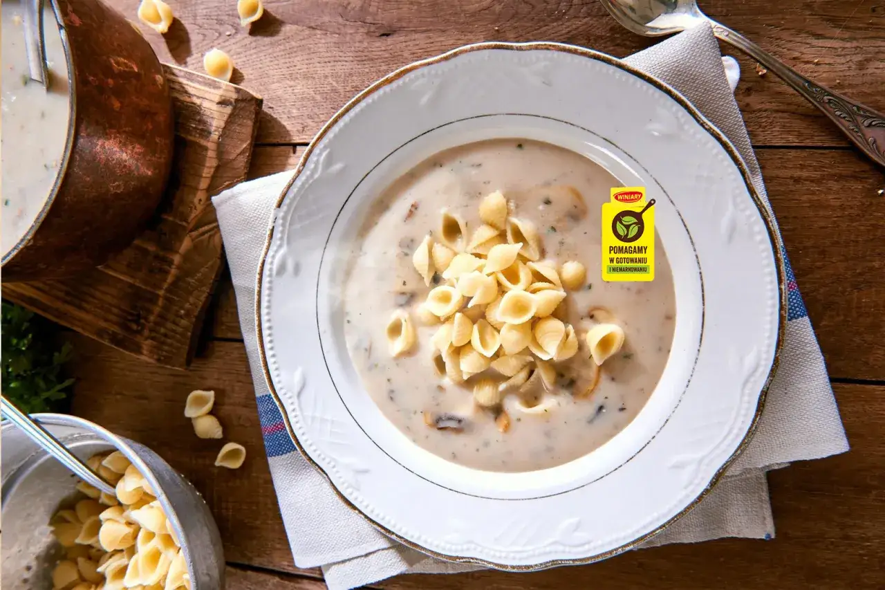 Aksamitna zupa pieczarkowa z makaronem w kształcie muszelek, podana w eleganckiej misce. Obok garnek z zupą i miska z makaronem.